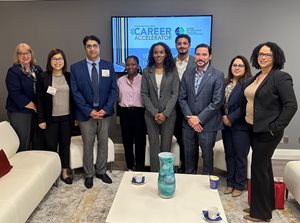Career Accelerators standing in OBA member lounge in front of a TV screen with Career Accelerator Program logo