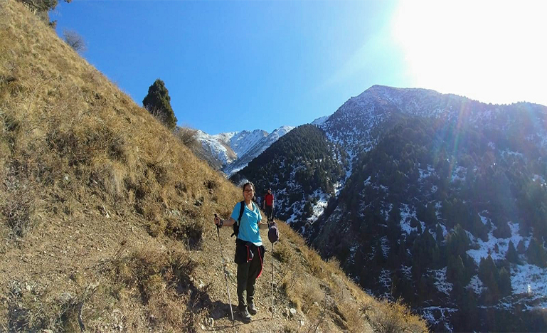 Woman with Hiking poles standing on a hillside in Kyrgyzstan