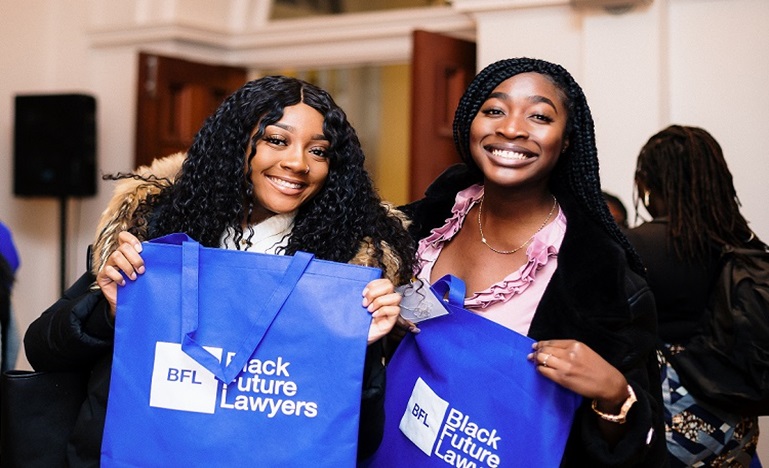 Two black women holding blue Black Future Lawyer bags