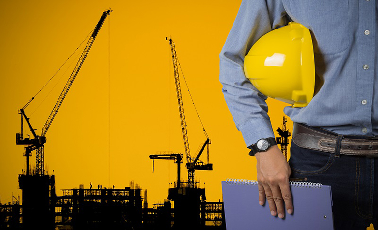 man with construction helmet under arm, construction rig in background