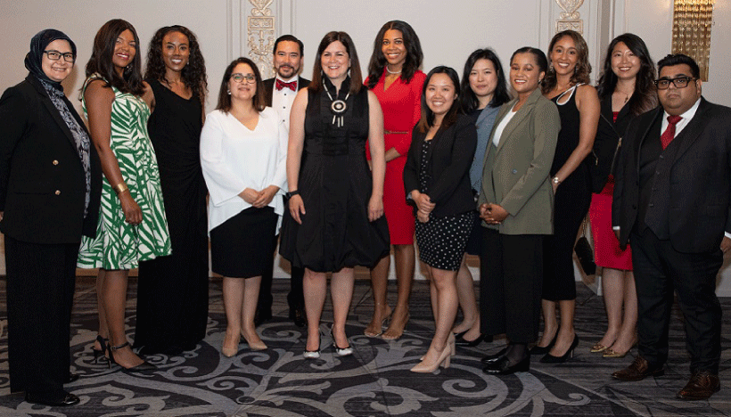 photo of OBA Career Accelerator participants, standing in OBA member lounge in front of TV screen with Career Accelerator logo