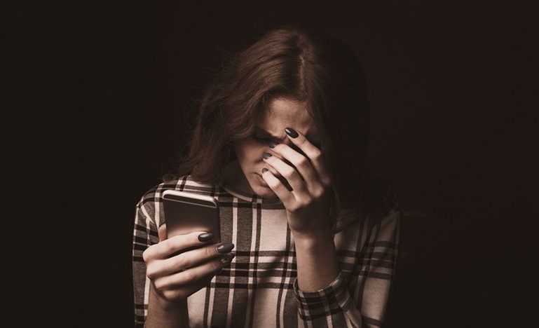 young woman looking at phone and hanging head in shame and irritation