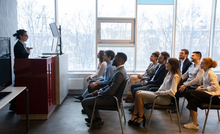 Professionnelle d'affaires donnant une présentation à un groupe diversifié de collègues attentifs dans une salle de conférence moderne.