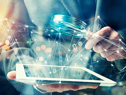 Person in a suit (only their torso and arms visible) holds a magnifying glass over a tablet from which bits of code and data are emanating