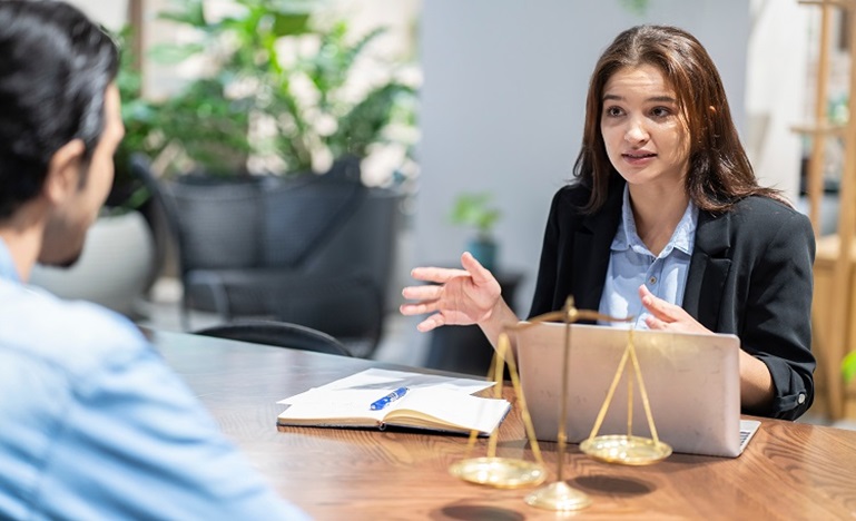 Woman lawyer sitting at a desk advising a male client