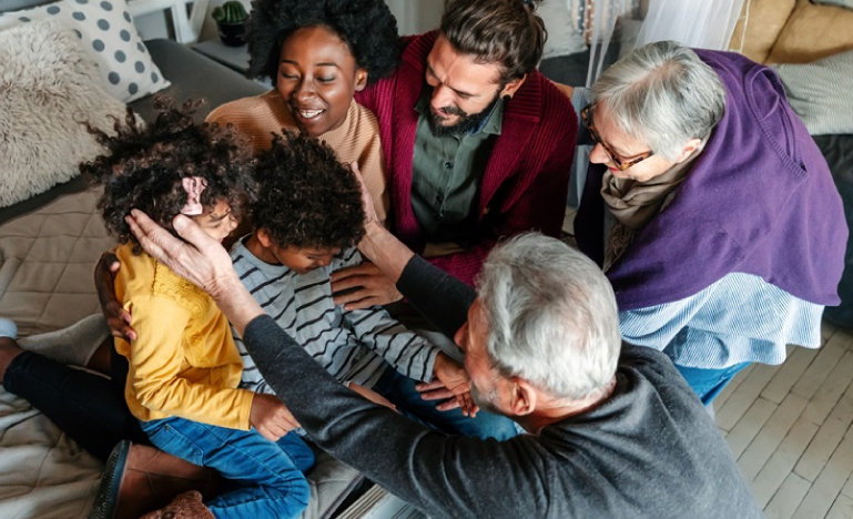 Happy multigenerational family gathered around two young children, sharing a joyful moment at home.