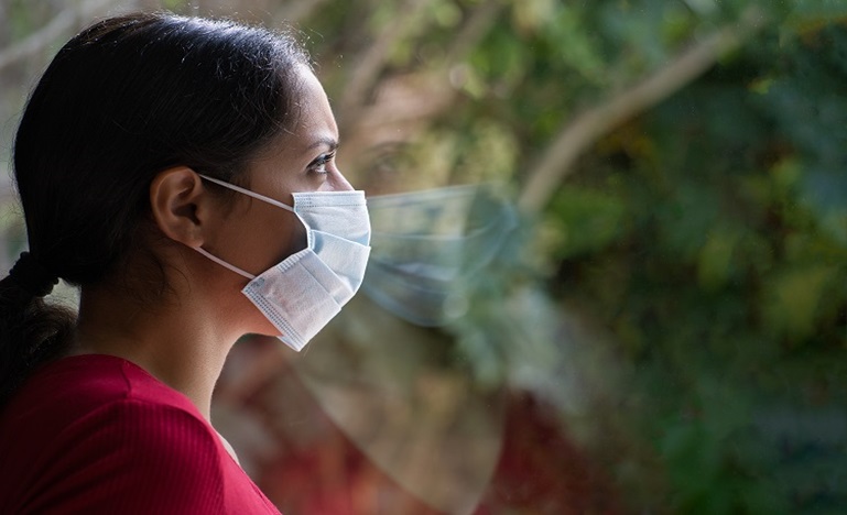 Woman with face mask looking out window