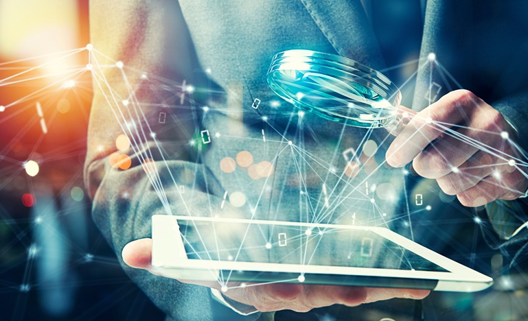 Person in a suit (only their torso and arms visible) holds a magnifying glass over a tablet from which bits of code and data are emanating