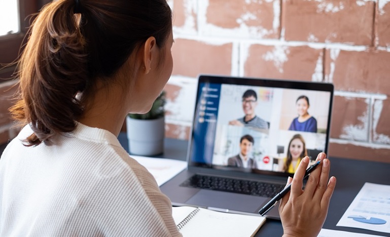 Lady looking at laptop while virtual conferencing with four other people