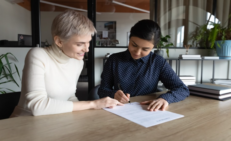 Lawyer seated at a table with client, helping them complete form