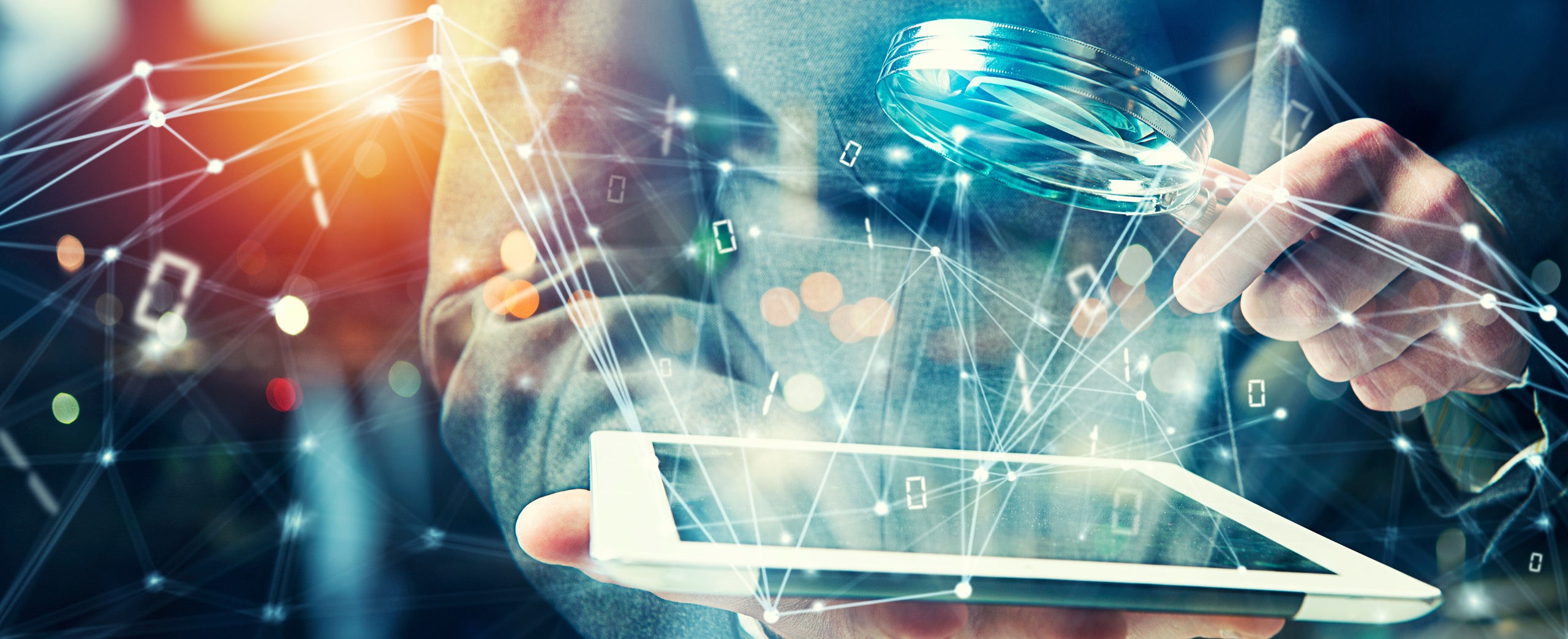 Person in a suit (only their torso and arms visible) holds a magnifying glass over a tablet from which bits of code and data are emanating