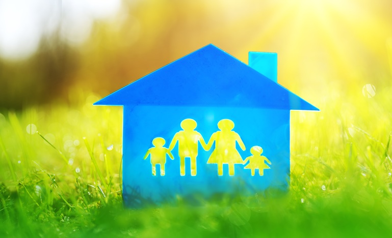 picture of blue house with silhouettes of four family members, two children and two adults, holding hands inside, all situated on a green-grass field