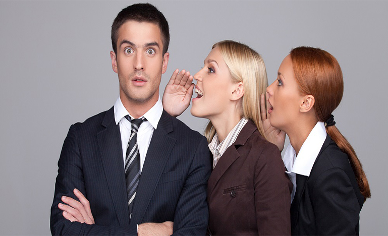 Two women talking into a man's ear